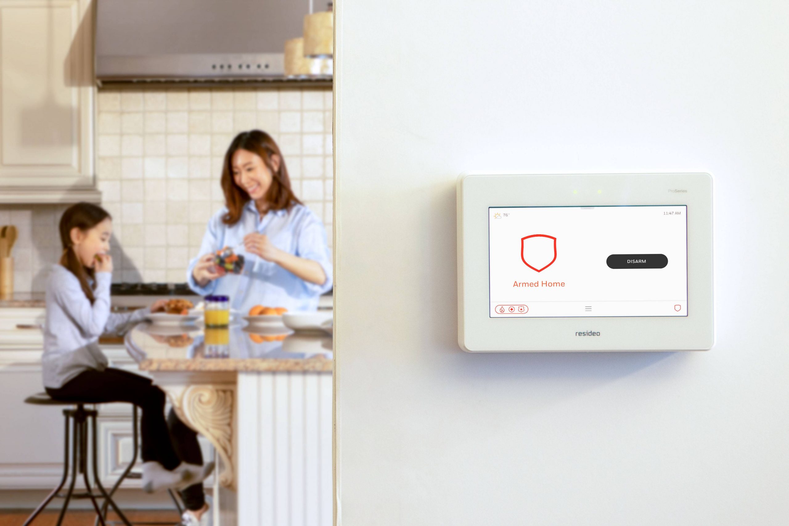 Woman and daughter in kitchen with alarm system on