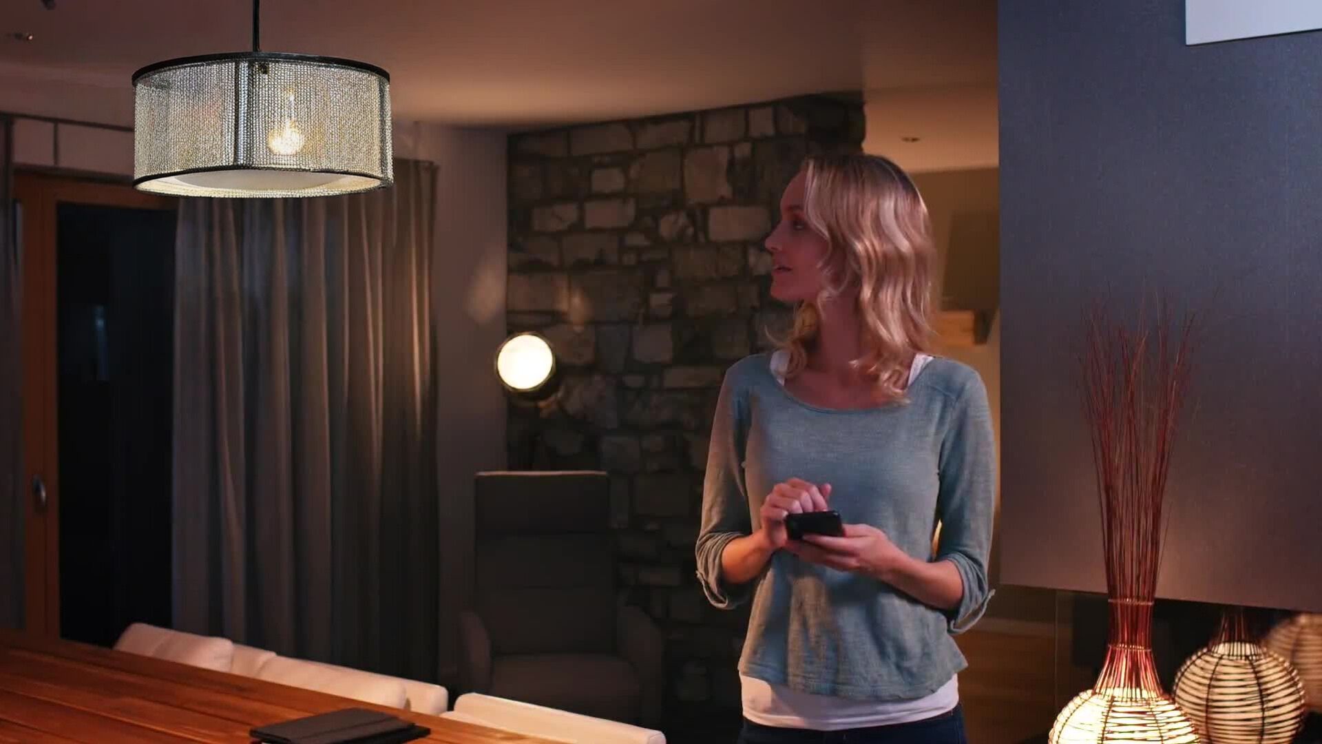 A woman uses a cell phone with the Total Connect App to use home automation features that turn on the lights in her home.